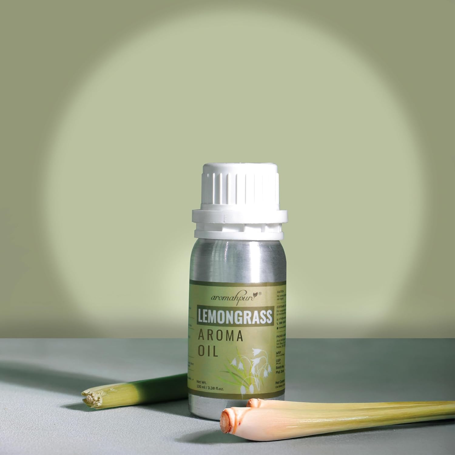 Bottle of lemongrass aroma oil with fresh lemongrass stalks on a neutral background