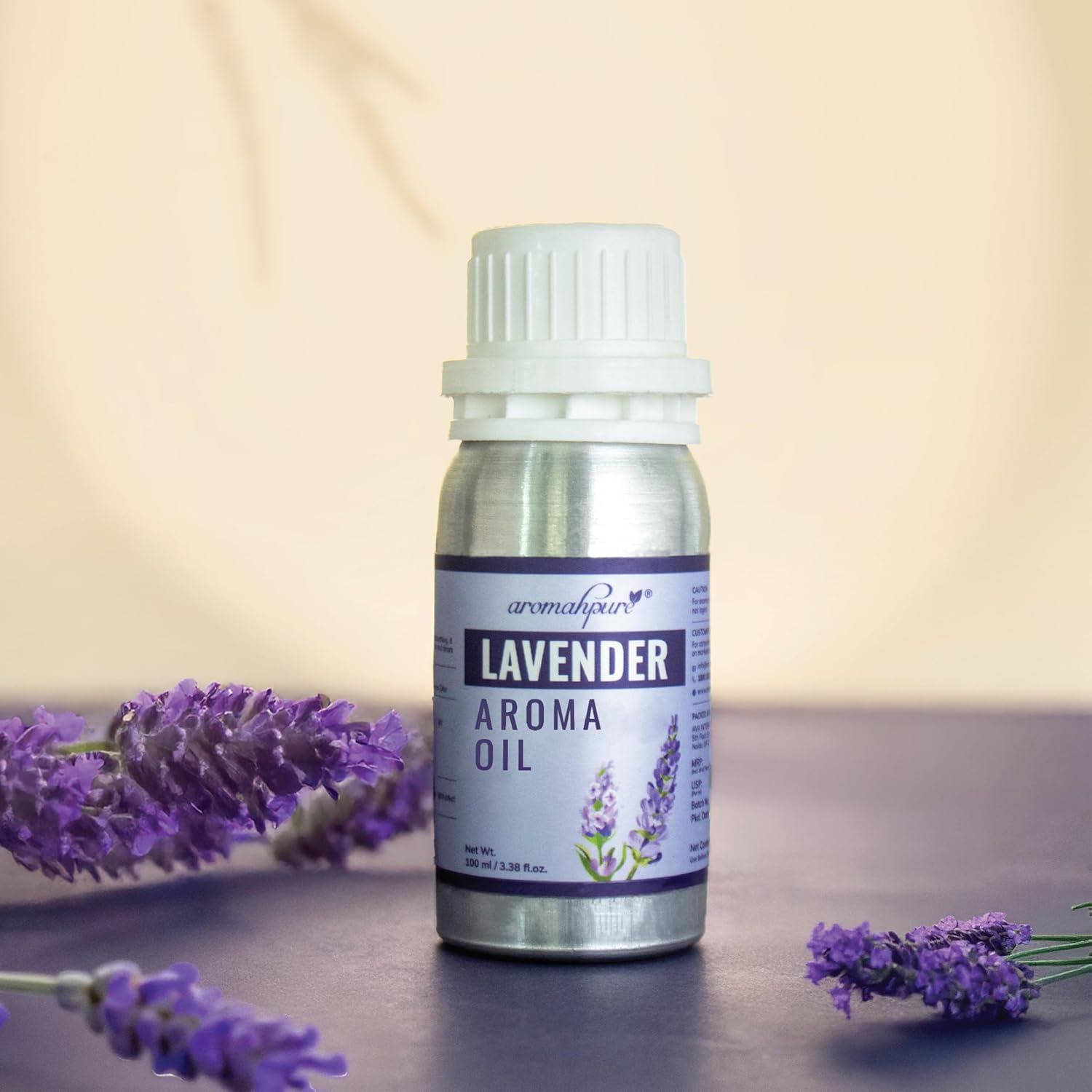 A bottle of aromasource Lavender Aroma Oil stands on a dark surface with lavender sprigs placed around it against a soft beige background.